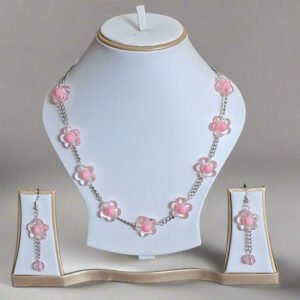 Necklace with pink floral pendants on a white stand against a dark background