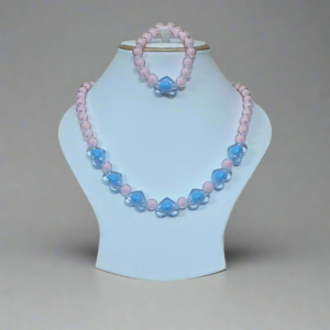 Necklace with pink and blue beads on a light blue stand against a green leafy background
