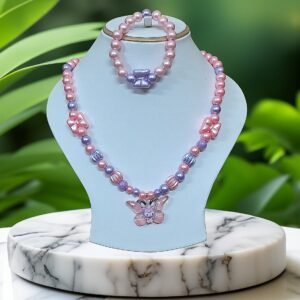 Pink and purple beaded necklace with butterfly pendant on a light blue stand against a green leafy background.
