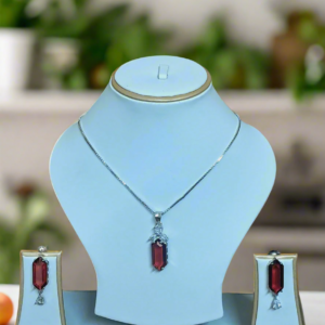 Elegant pendant set featuring a red ruby centerpiece and CZ stones on a silver-plated chain by Garimas.