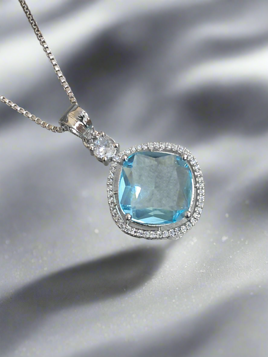 background-editor_output_18d218d0-c5fc-4e9f-9919-0cecc41515bb-1 Aqua blue pendant with CZ studs on a silver-plated chain, perfect for any occasion by Garimas.
