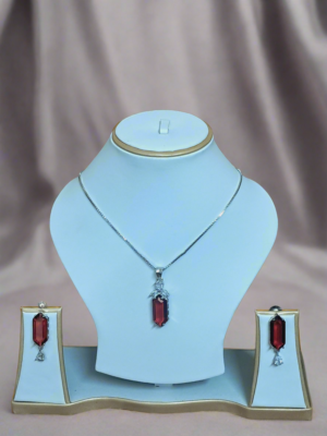 Elegant Garimas pendant set featuring red ruby and CZ stones on a silver-plated chain, showcased on a jewelry display.
